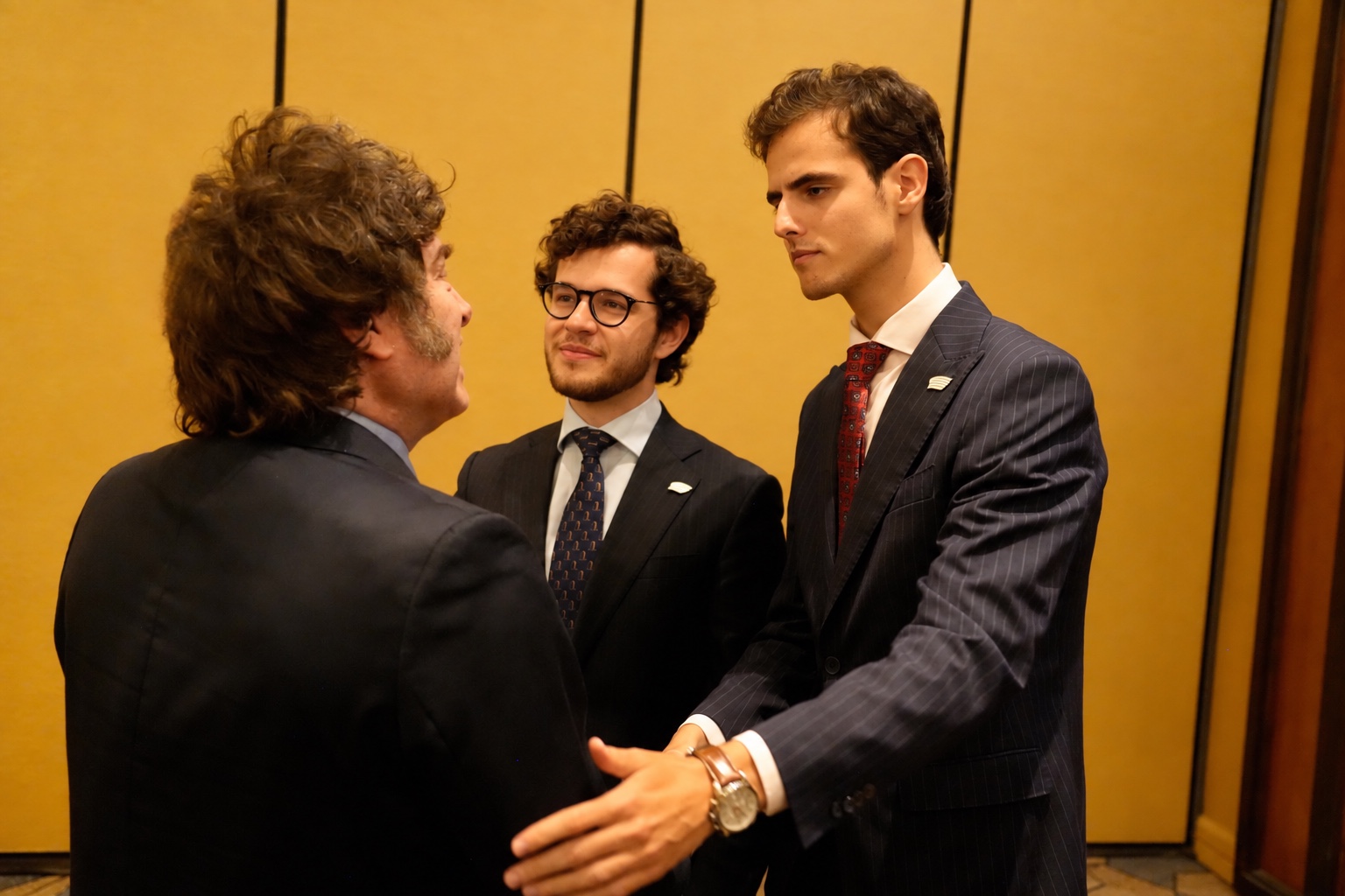 Javier Milei conversa con dos asistentes durante un encuentro